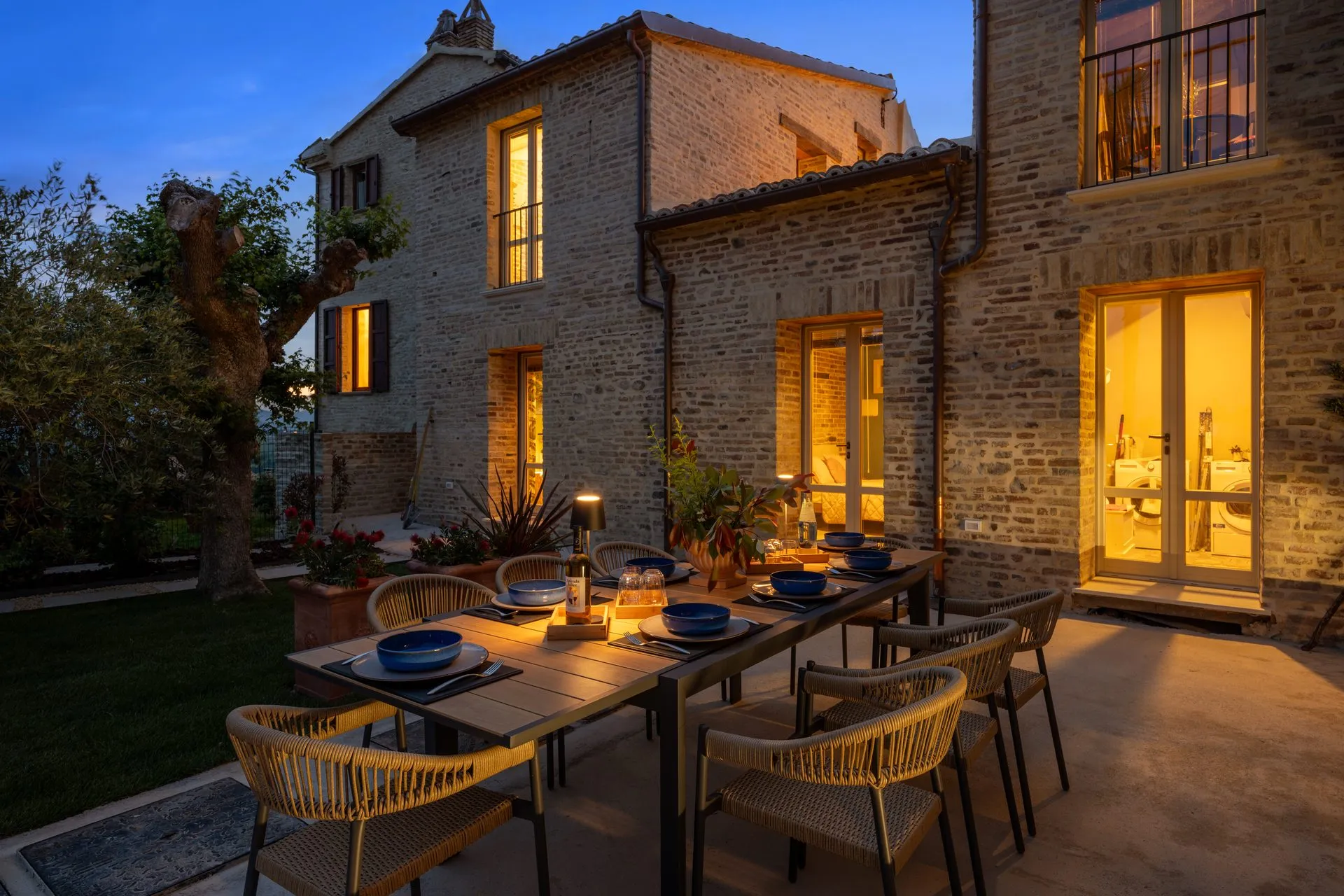 Innenhof am Abend, gedeckte Tafel vor warm erleuchteten Fenstern