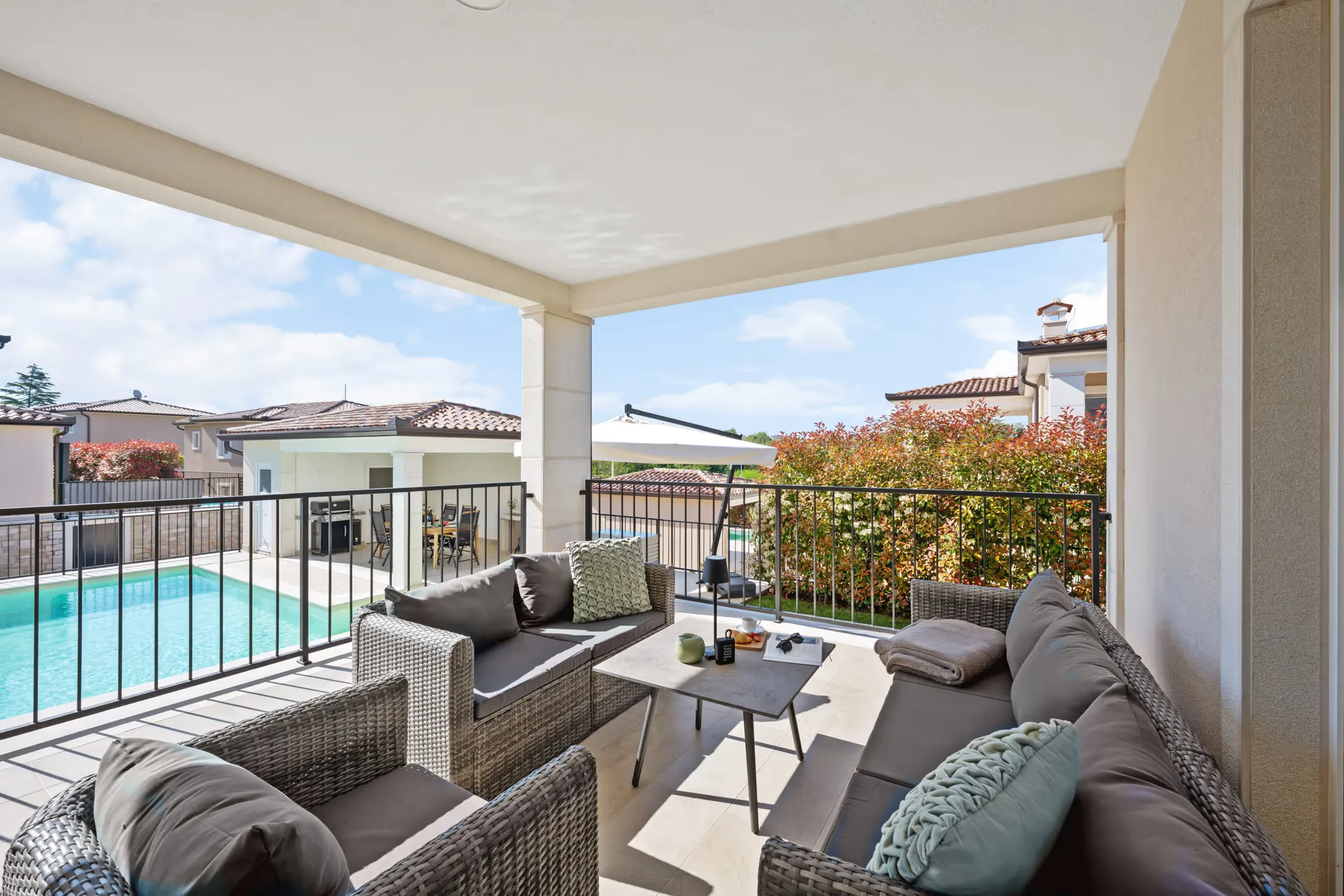 Überdachte Terrasse mit Loungemöbeln und Blick auf den Pool