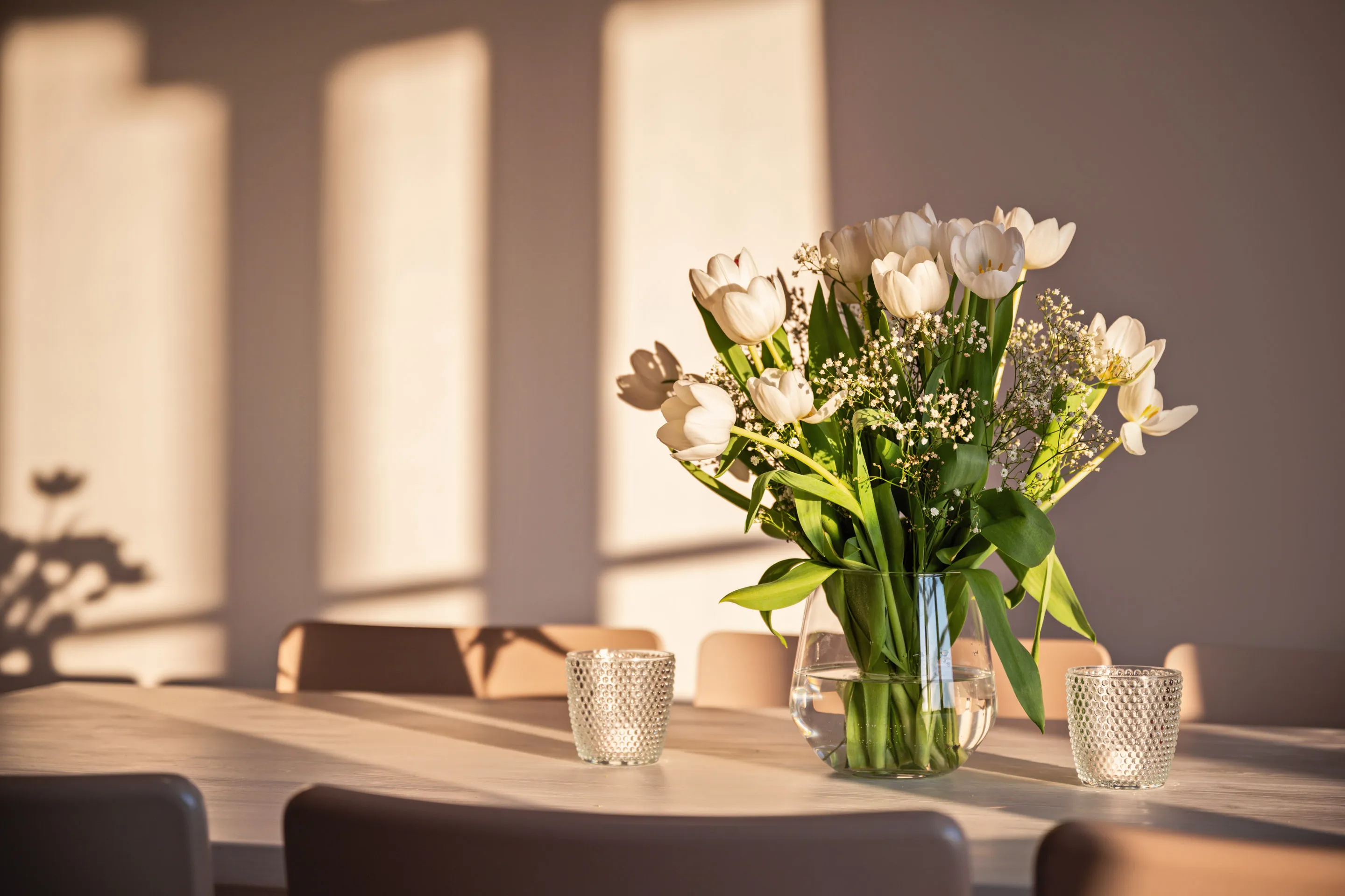 Sonnendurchflutet gedeckter Tisch mit frischen Blumen in einer von Ivy fotografierten Ferienwohnung