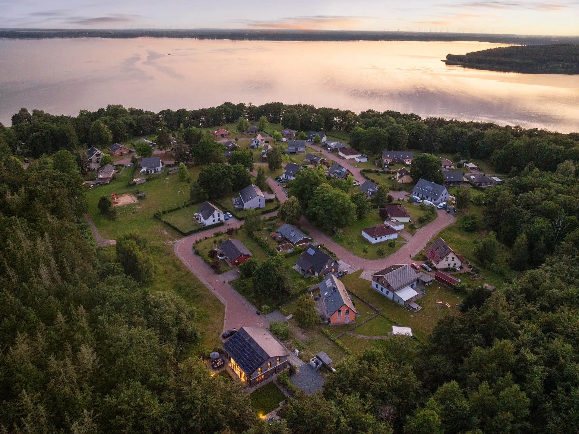 Luftaufnahme der Ferienhaussiedlung am Seeufer im Abendlicht
