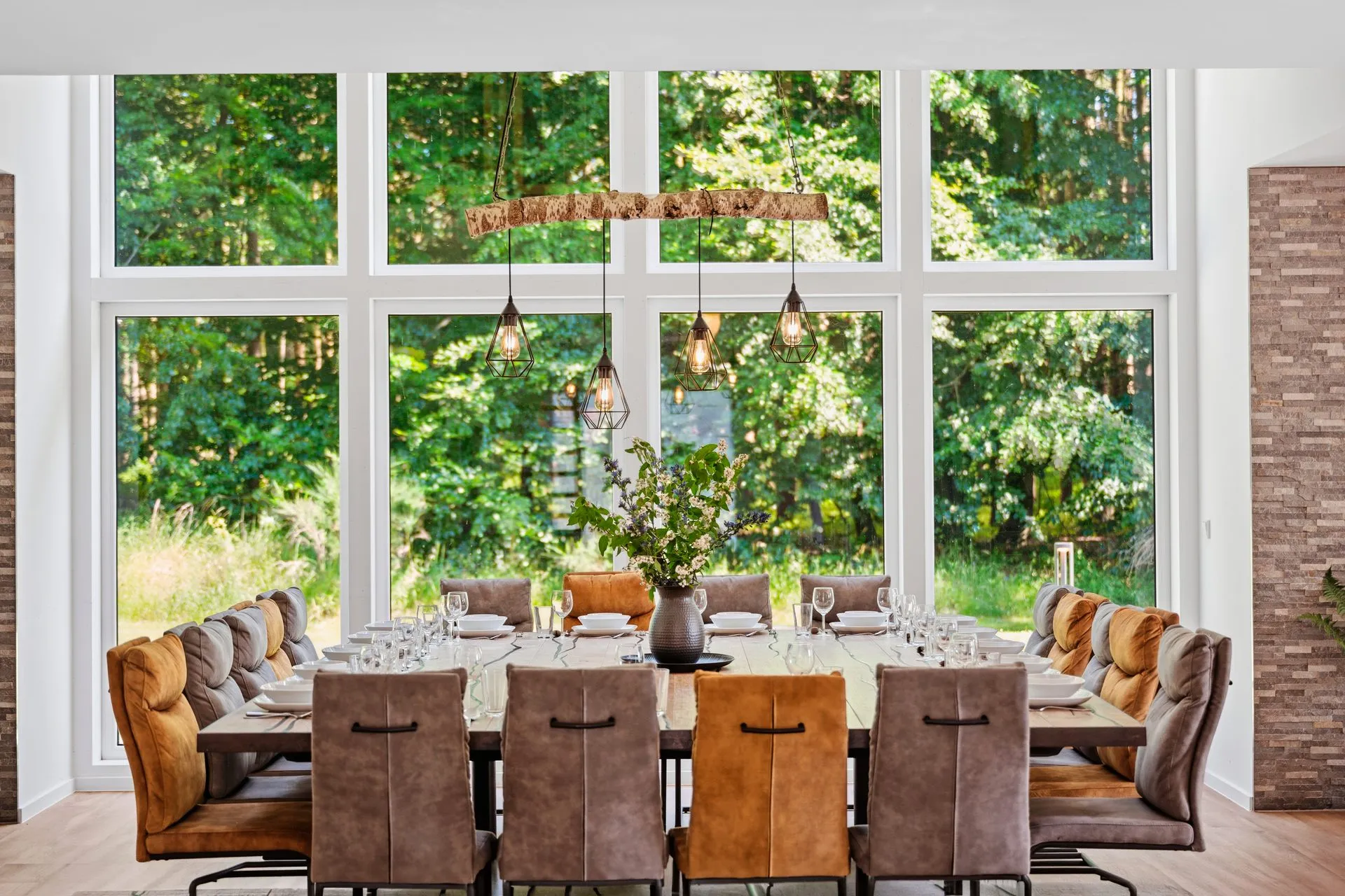 Lange Tafel vor einer raumhohen Fensterfront mit Blick in den Wald