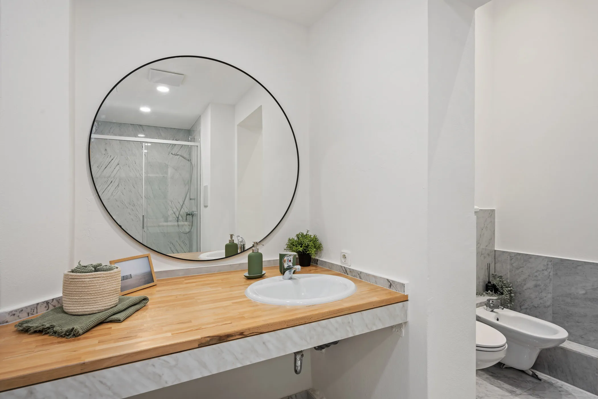 Modernes Badezimmer mit rundem Spiegel und Holzwaschtisch