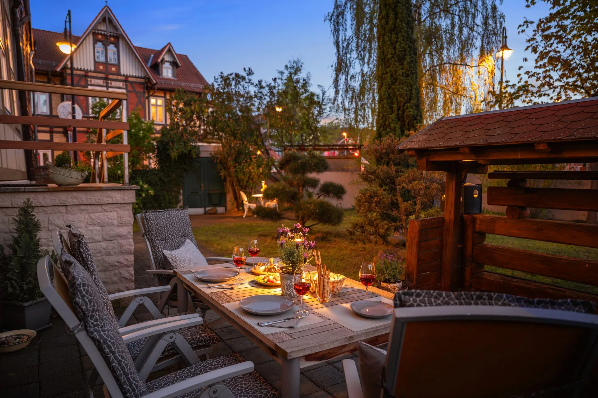 Terrasse in der Abenddämmerung mit Kerzen, dahinter Fachwerkhäuser