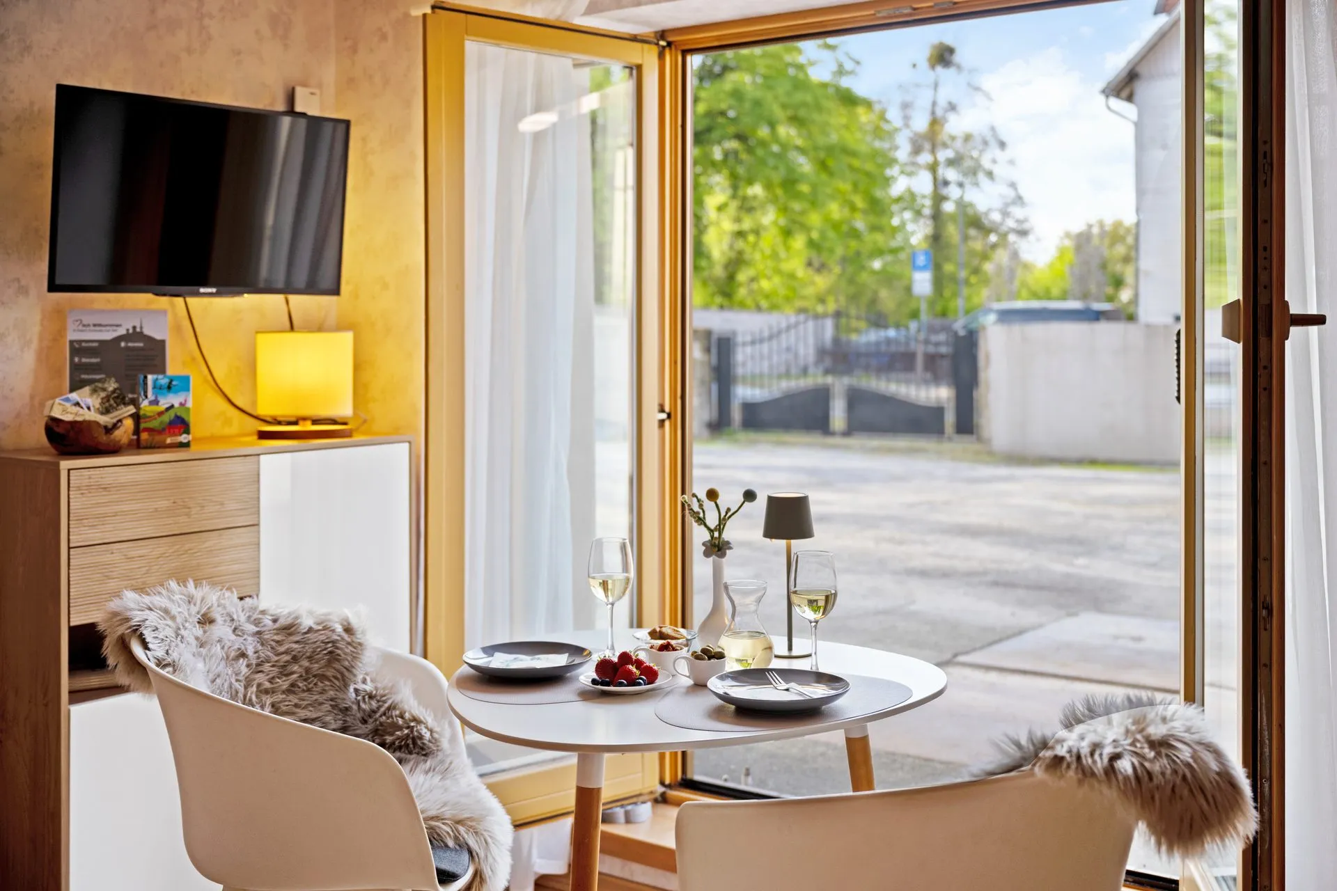Gedeckter Tisch vor der geöffneten Terrassentür, Abendlicht im Zimmer